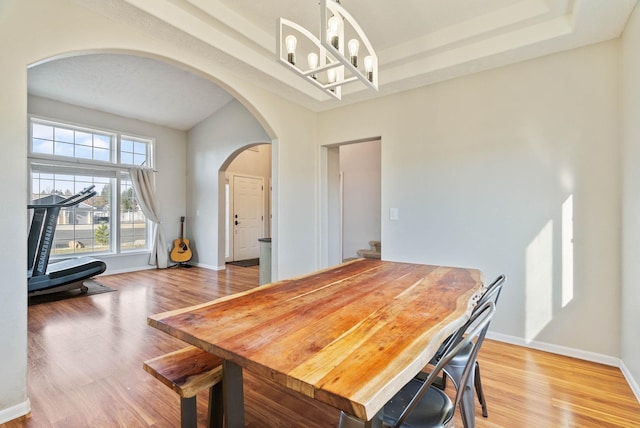 14706 N Mckinnon Ct, Mead, WA 99021 - dining area featuring arched walkways, a chandelier, light wood-type flooring, and a tray ceiling