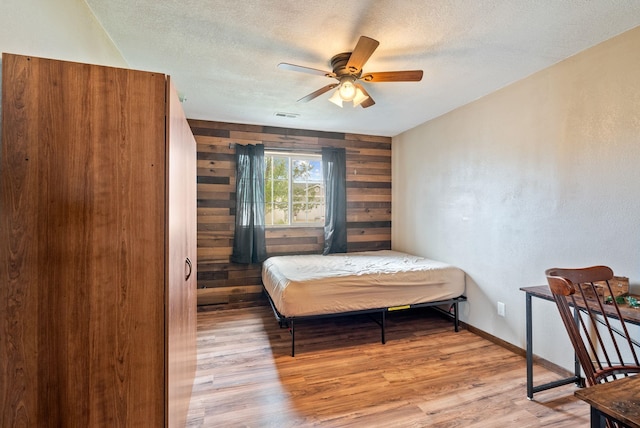 724 E Joshua Dr, Medical Lake, WA 99022 - bedroom with wood finished floors, wooden walls, a textured ceiling, and ceiling fan