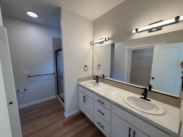 4420 S Willow Ln, Spokane, WA 99216 - bathroom featuring a stall shower, double vanity, wood finished floors, a walk in closet, and backsplash