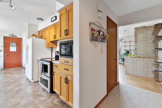 3205 W Hoffman Ave, Spokane, WA 99205 - kitchen with double oven range, black microwave, light countertops, and freestanding refrigerator