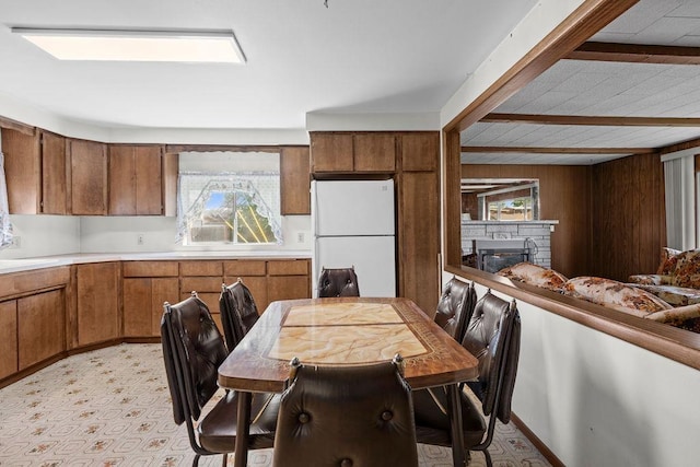2920 N Regal St, Spokane, WA 99207 - kitchen with freestanding refrigerator, brown cabinets, light countertops, a fireplace, and wood walls