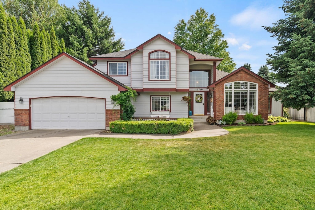 15718 E 21st Ct, Spokane Valley, WA 99037 - view of front of home featuring concrete driveway, a garage, a front lawn, and brick siding