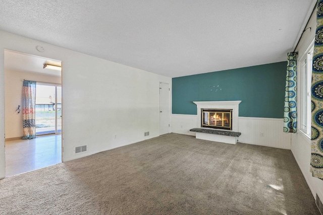 621 E Dalke Ave, Spokane, WA 99208 - unfurnished living room featuring a glass covered fireplace, a wainscoted wall, a textured ceiling, and carpet