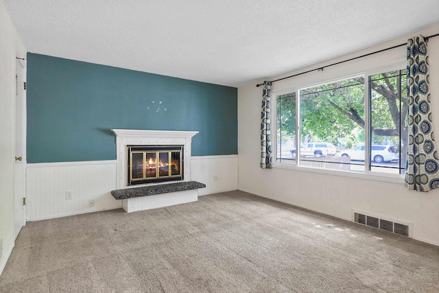 621 E Dalke Ave, Spokane, WA 99208 - unfurnished living room with a textured ceiling, plenty of natural light, a glass covered fireplace, wainscoting, and carpet flooring