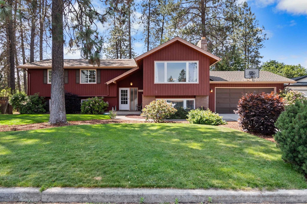 11905 N Atlantic St, Spokane, WA 99218 - bi-level home featuring an attached garage, a front yard, roof with shingles, and brick siding