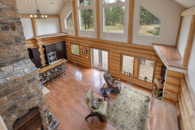 15611 W Pine Bluff Rd, Nine Mile Falls, WA 99026 - living area featuring log walls, a high ceiling, wood finished floors, french doors, and a chandelier
