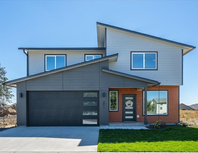 2091 W Walker Ave, Spokane, WA 99208 - contemporary house featuring an attached garage, concrete driveway, a front yard, and covered porch