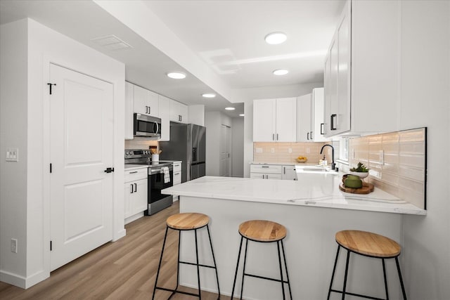 2091 W Walker Ave, Spokane, WA 99208 - kitchen with appliances with stainless steel finishes, a peninsula, recessed lighting, light wood finished floors, and decorative backsplash