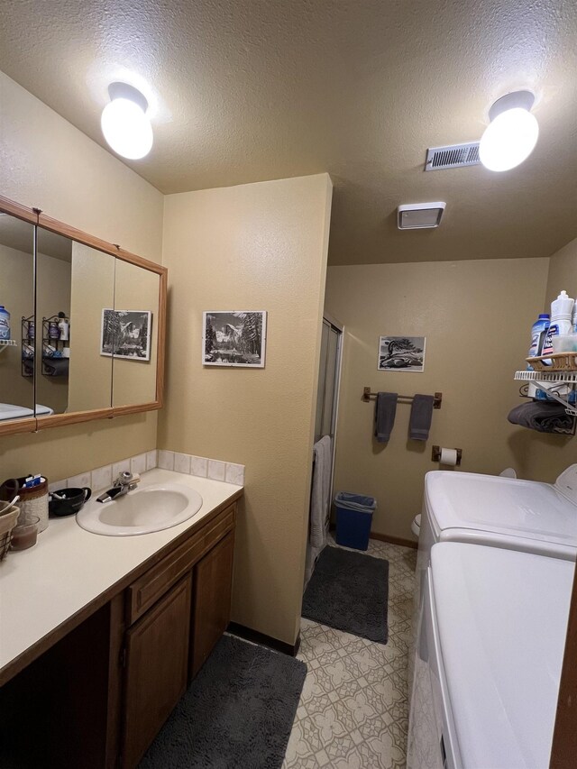 4605 W Pinto Rd, Cheney, WA 99004 - bathroom with washer and dryer, vanity, a shower, a textured ceiling, and tile patterned floors