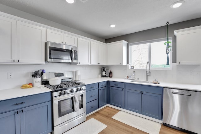 4538 W Brookfield Ave, Spokane, WA 99208 - kitchen featuring stainless steel appliances, blue cabinets, white cabinets, tasteful backsplash, and light wood finished floors