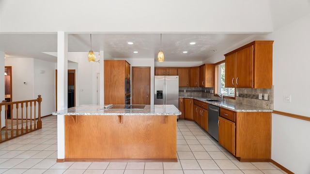 1220 E Brierwood Dr, Spokane, WA 99218 - kitchen with appliances with stainless steel finishes, brown cabinets, backsplash, light stone counters, and recessed lighting