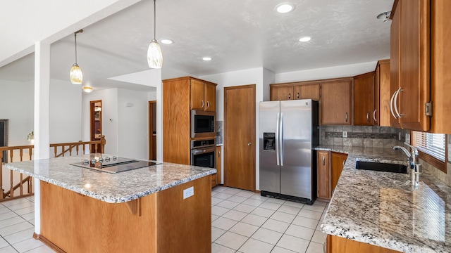 1220 E Brierwood Dr, Spokane, WA 99218 - kitchen featuring appliances with stainless steel finishes, brown cabinets, a breakfast bar, light tile patterned floors, and a center island