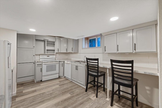 1007 W 15th Ave, Spokane, WA 99203 - kitchen featuring white appliances, open shelves, light wood-type flooring, backsplash, and a breakfast bar