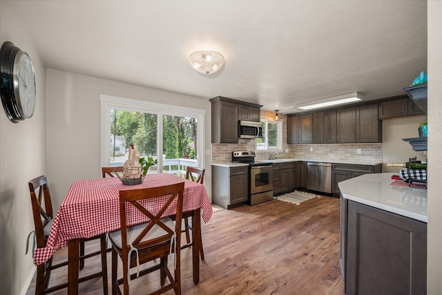 426 E 17th St, Spokane, WA 99203 - kitchen featuring appliances with stainless steel finishes, dark brown cabinets, tasteful backsplash, wood finished floors, and healthy amount of natural light