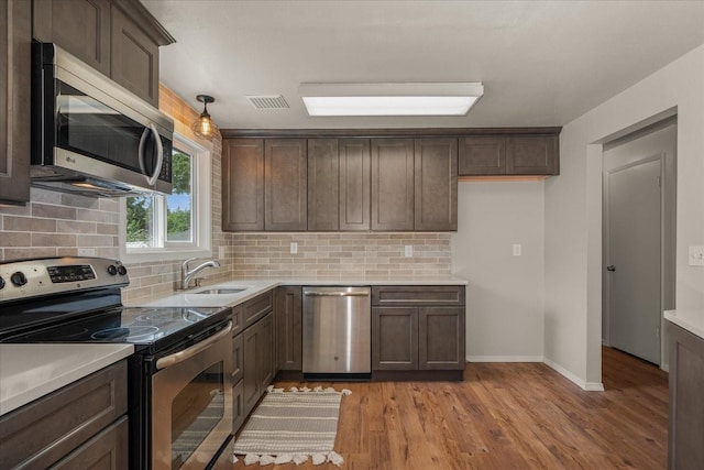 426 E 17th St, Spokane, WA 99203 - kitchen with appliances with stainless steel finishes, decorative backsplash, light countertops, and light wood-style flooring