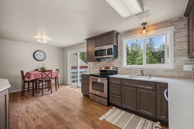 426 E 17th St, Spokane, WA 99203 - kitchen featuring stainless steel appliances, decorative backsplash, light countertops, light wood-style floors, and dark brown cabinets