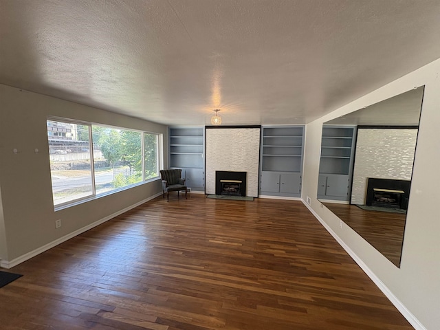 820/828 W 11th Ave, Spokane, WA 99204 - unfurnished living room with a large fireplace, wood finished floors, a textured ceiling, and built in shelves