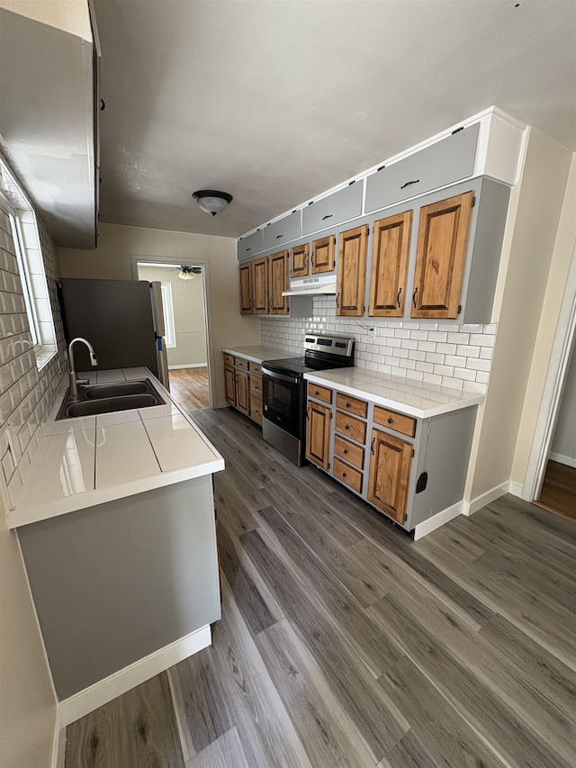 820/828 W 11th Ave, Spokane, WA 99204 - kitchen featuring stainless steel appliances, brown cabinetry, decorative backsplash, and under cabinet range hood