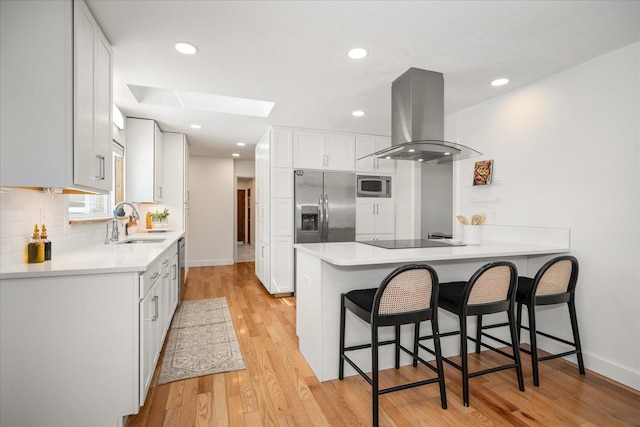 915 W 32nd Ave, Spokane, WA 99203 - kitchen featuring island exhaust hood, stainless steel appliances, a skylight, a peninsula, and a kitchen breakfast bar