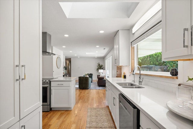 915 W 32nd Ave, Spokane, WA 99203 - kitchen featuring appliances with stainless steel finishes, wall chimney range hood, light countertops, open floor plan, and light wood-style floors