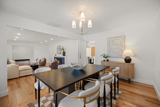 915 W 32nd Ave, Spokane, WA 99203 - dining room with light wood-type flooring, a chandelier, a lit fireplace, and recessed lighting