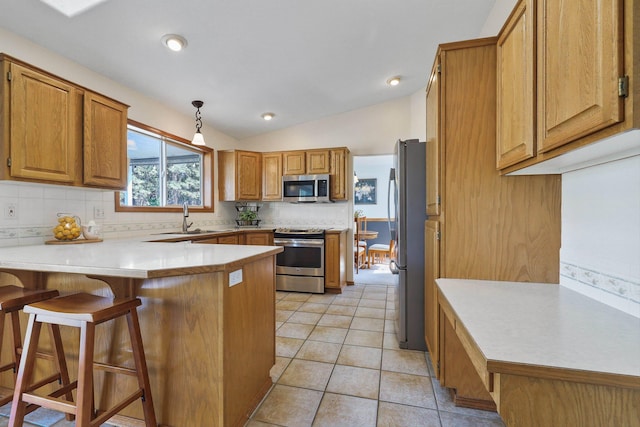 15618 N Chronicle Ct, Mead, WA 99021 - kitchen featuring stainless steel appliances, a peninsula, decorative backsplash, brown cabinets, and lofted ceiling