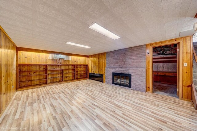 1003 W Eastmont Way, Spokane, WA 99208 - unfurnished living room featuring wooden walls, a fireplace, and wood finished floors