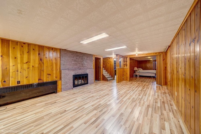 1003 W Eastmont Way, Spokane, WA 99208 - unfurnished living room with wooden walls, a fireplace, wood finished floors, and stairway