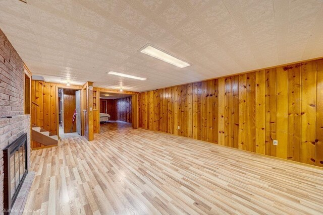 1003 W Eastmont Way, Spokane, WA 99208 - unfurnished living room featuring a brick fireplace, light wood-style flooring, and wooden walls