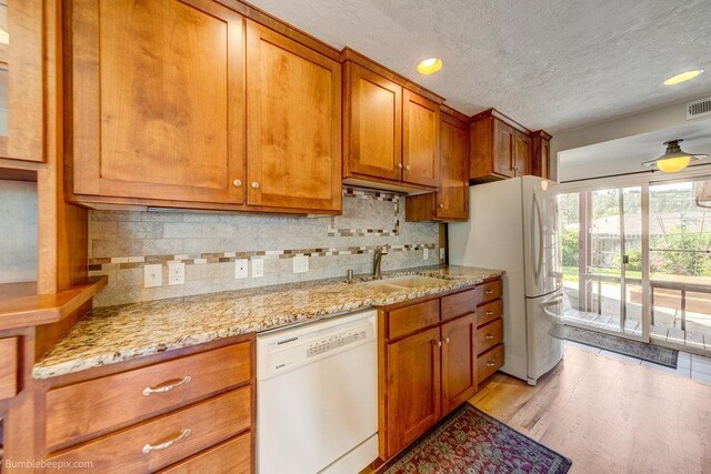 1003 W Eastmont Way, Spokane, WA 99208 - kitchen with white appliances, brown cabinetry, a textured ceiling, backsplash, and light wood finished floors