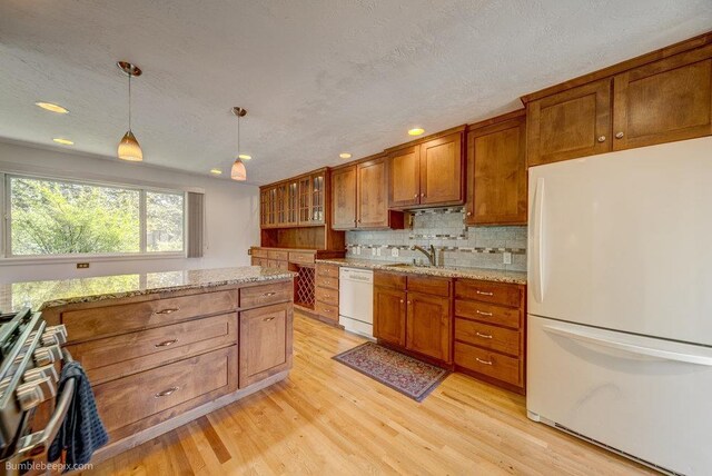 1003 W Eastmont Way, Spokane, WA 99208 - kitchen with white appliances, brown cabinets, light wood finished floors, decorative light fixtures, and backsplash