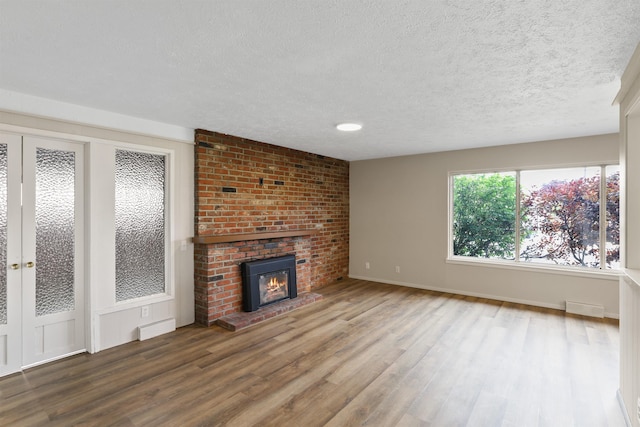 5804 N Maple St, Spokane, WA 99205 - unfurnished living room with wood finished floors, a textured ceiling, and a brick fireplace