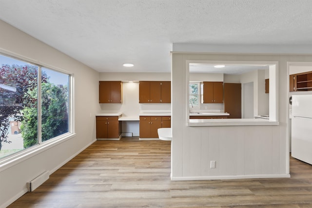 5804 N Maple St, Spokane, WA 99205 - kitchen with freestanding refrigerator, baseboard heating, light wood-style floors, light countertops, and brown cabinets