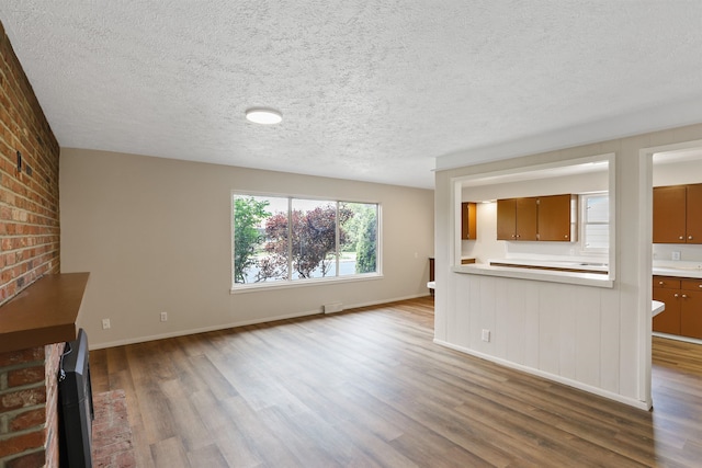 5804 N Maple St, Spokane, WA 99205 - unfurnished living room featuring wood finished floors, a textured ceiling, and brick wall