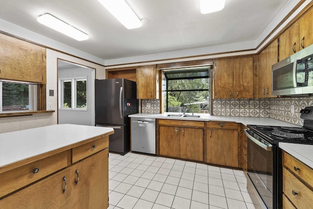 812 W Westover Rd, Spokane, WA 99218 - kitchen featuring stainless steel appliances, light countertops, light tile patterned floors, brown cabinets, and decorative backsplash