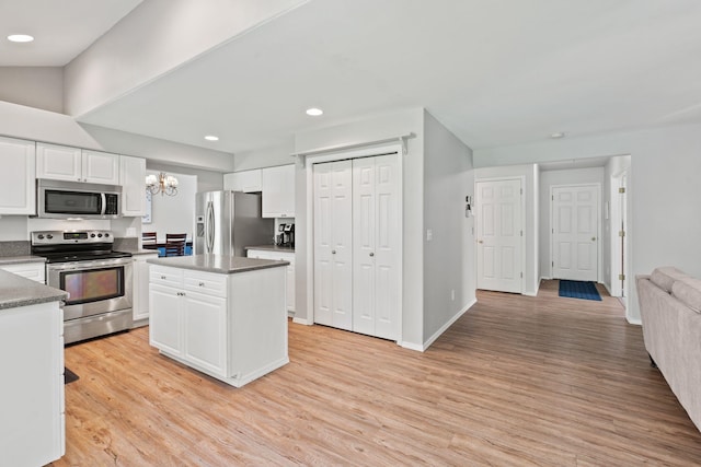 6610 S Echo Ridge St, Spokane, WA 99224 - kitchen with appliances with stainless steel finishes, a chandelier, light wood finished floors, white cabinetry, and a kitchen island