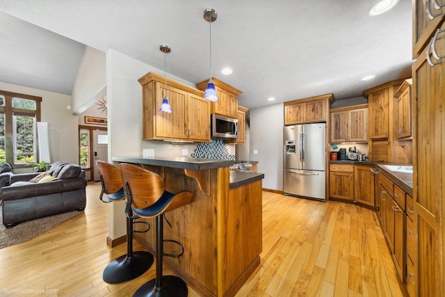 1629 S Royal St, Spokane, WA 99224 - kitchen featuring appliances with stainless steel finishes, dark countertops, a peninsula, brown cabinetry, and recessed lighting