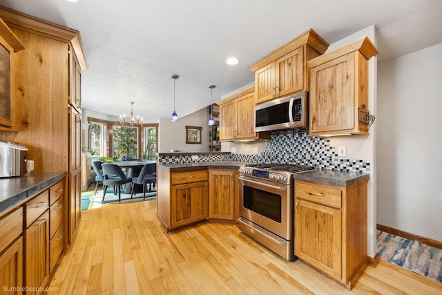 1629 S Royal St, Spokane, WA 99224 - kitchen featuring stainless steel appliances, a peninsula, dark countertops, decorative backsplash, and a chandelier