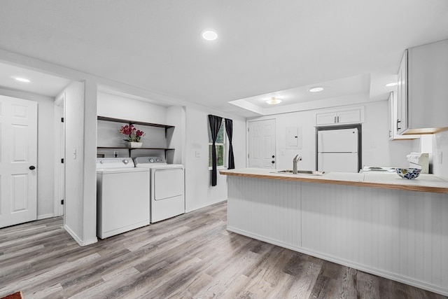 610 N 1st St, Springdale, WA 99173 - kitchen with freestanding refrigerator, range, light wood-style floors, a peninsula, and white cabinetry