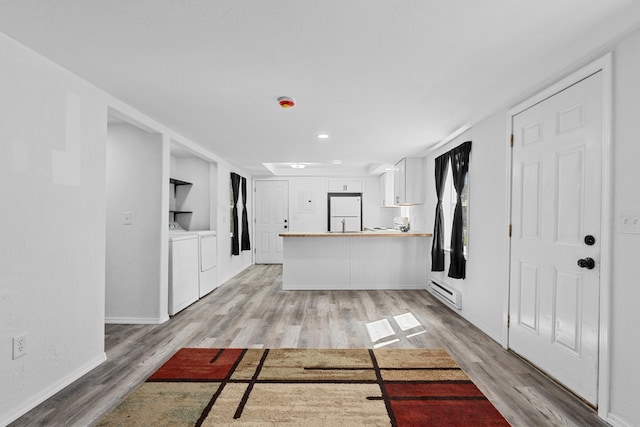610 N 1st St, Springdale, WA 99173 - kitchen with washer and dryer, freestanding refrigerator, light wood finished floors, a peninsula, and a baseboard heating unit
