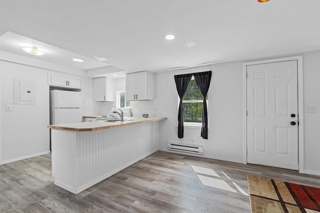 610 N 1st St, Springdale, WA 99173 - kitchen with freestanding refrigerator, baseboard heating, a peninsula, light wood-style floors, and light countertops