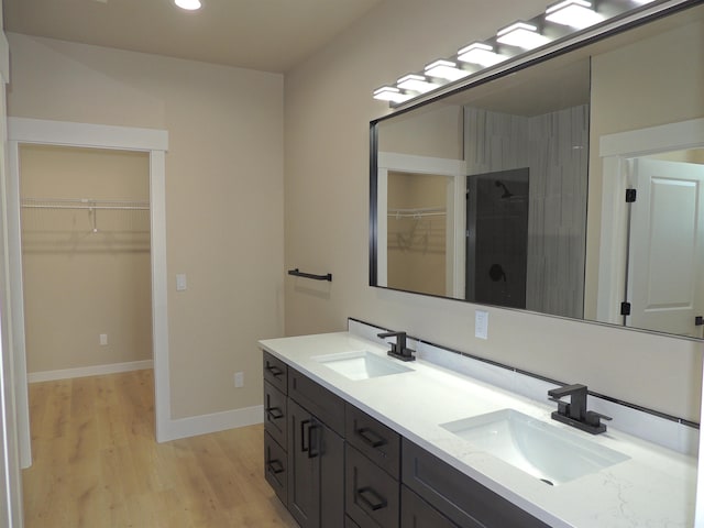 516 SW Alder St, Wilbur, WA 99185 - bathroom featuring double vanity, wood finished floors, a walk in closet, recessed lighting, and a tile shower