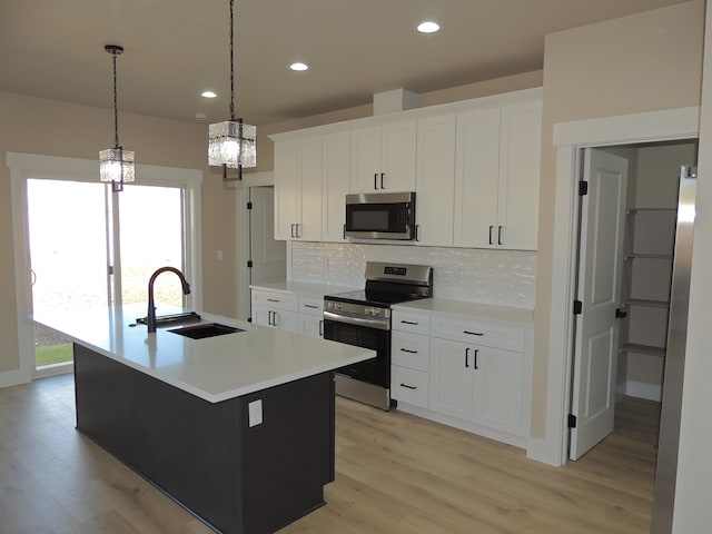 516 SW Alder St, Wilbur, WA 99185 - kitchen with appliances with stainless steel finishes, light wood-style floors, decorative backsplash, a center island with sink, and a chandelier
