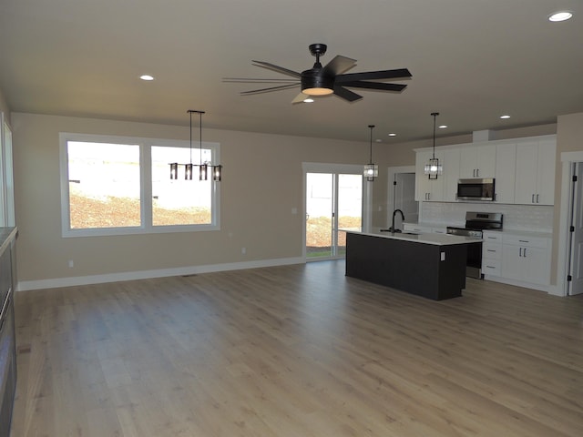 516 SW Alder St, Wilbur, WA 99185 - kitchen with appliances with stainless steel finishes, open floor plan, a center island with sink, decorative backsplash, and recessed lighting