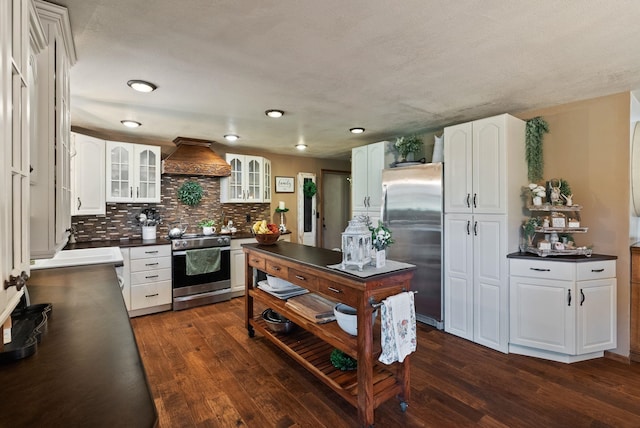 25210 E Bradshaw Rd, Fairfield, WA 99012 - kitchen with appliances with stainless steel finishes, dark countertops, premium range hood, glass insert cabinets, and dark wood-style flooring