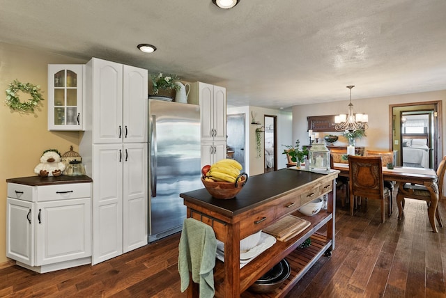 25210 E Bradshaw Rd, Fairfield, WA 99012 - kitchen with freestanding refrigerator, dark wood-type flooring, dark countertops, white cabinetry, and a chandelier