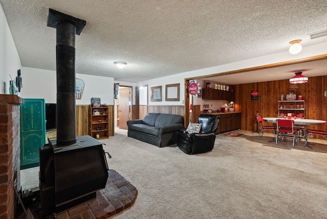 25210 E Bradshaw Rd, Fairfield, WA 99012 - living area featuring a wood stove, wood walls, carpet flooring, a wainscoted wall, and a textured ceiling