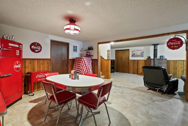 25210 E Bradshaw Rd, Fairfield, WA 99012 - dining area featuring wood walls, a wainscoted wall, tile patterned floors, a wood stove, and a textured ceiling