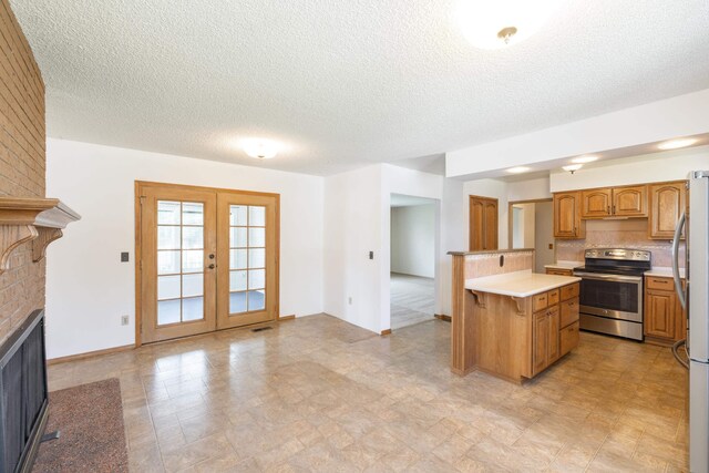 14006 E Cataldo Ave, Spokane Valley, WA 99216 - kitchen with stainless steel appliances, light countertops, a brick fireplace, a textured ceiling, and french doors