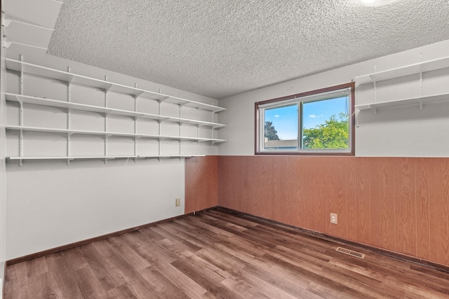 13015 E Mallon Ct, Spokane Valley, WA 99216 - unfurnished room featuring a wainscoted wall, dark wood finished floors, a textured ceiling, and wooden walls
